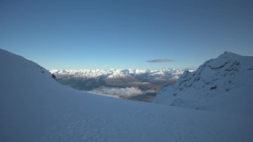 A white ground covered with snow in the middle of icy mountains and in the background a landscape of a mountain range with modems with their peaks covered in snow