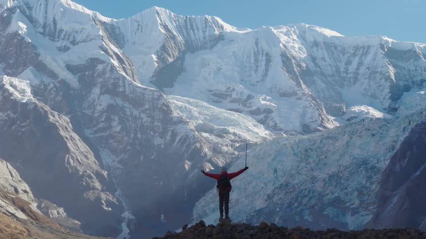 Person excited to reach the summit to view the enormous mountains across the way