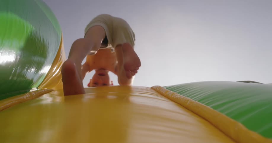 Boy climbs up an inflatable slide before sitting on top of it