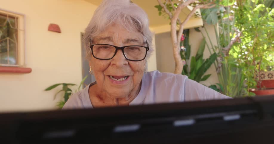 A grandmother and her grandson smile and talk while using a tablet