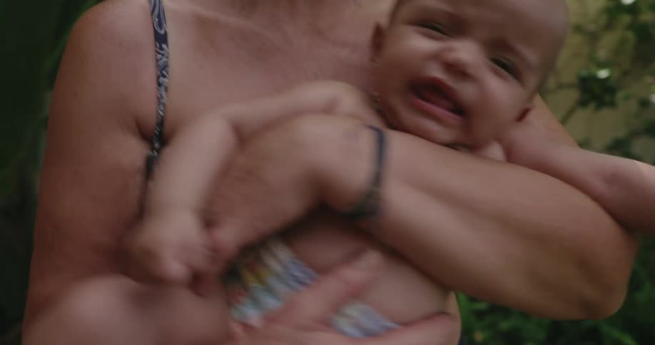 A mother gently rocks her infant in her arms