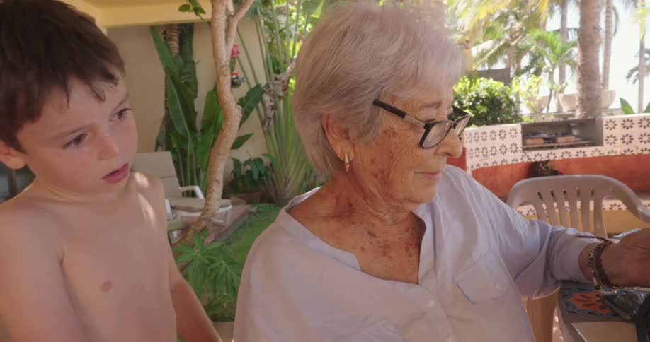 A grandmother and grandson look at a photo together