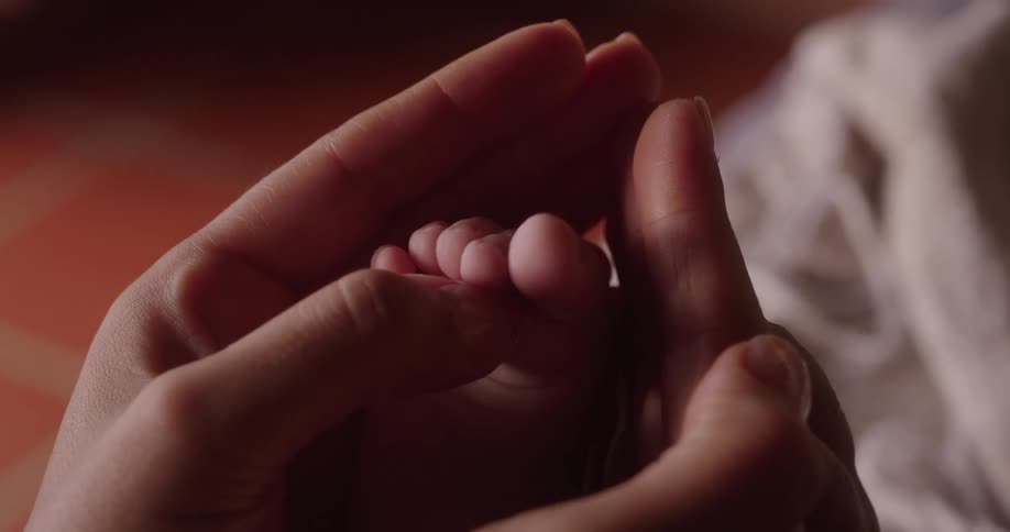 Pair of hands caressing a babys foot