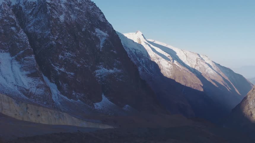 A mountain range landscape with snow covered peaks under a clear blue sky