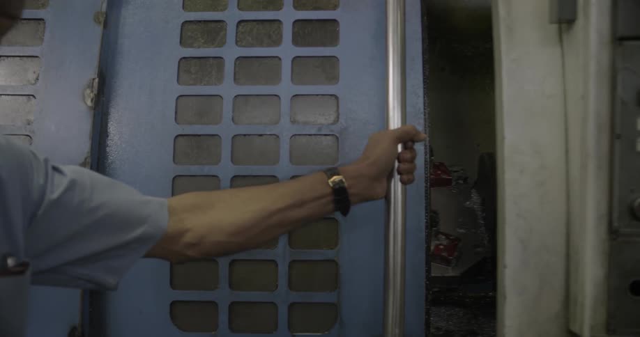 A man closes the door on a large machine