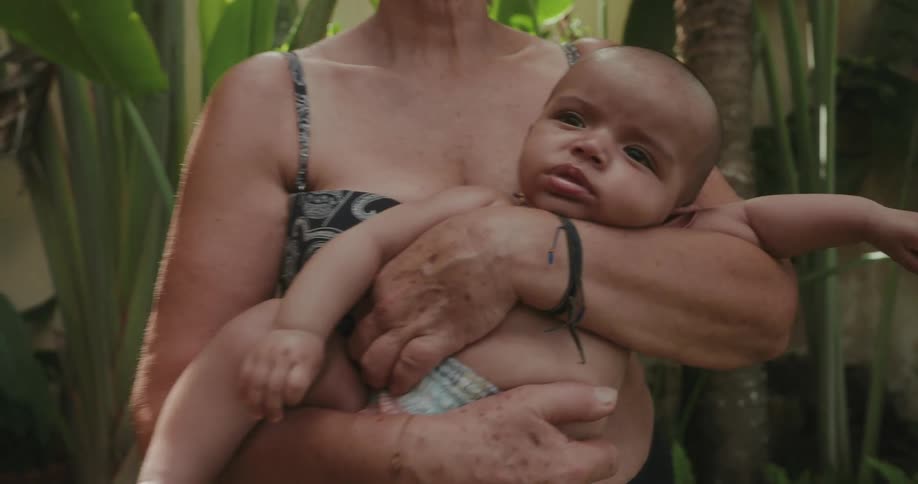 Grandmother sways while holding baby facing out in her arms