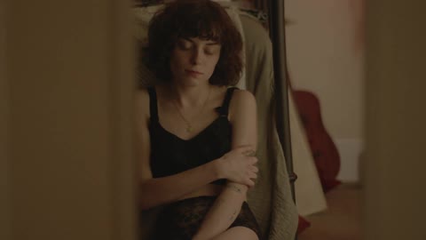 A woman sits on the floor of a bedroom
