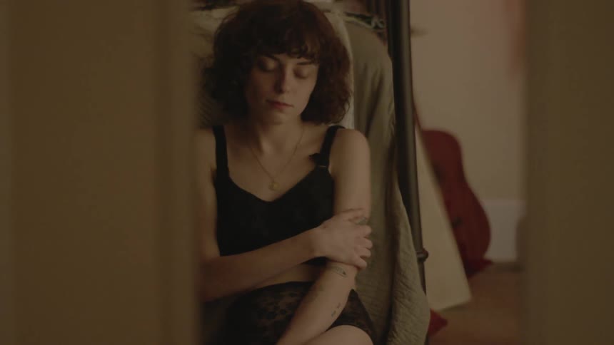 A woman sits on the floor of a bedroom