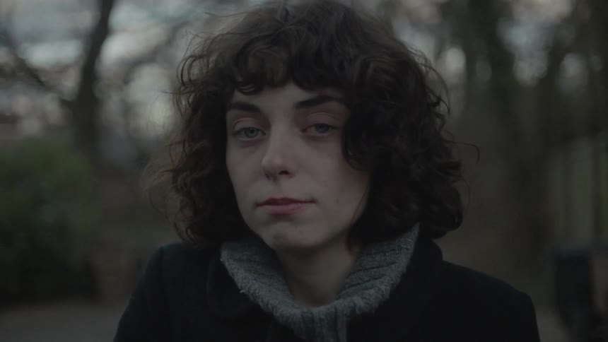 A woman is standing outside on a windy day