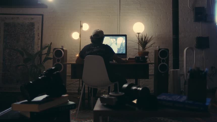 A person sits in a white chair looking at a television with images playing