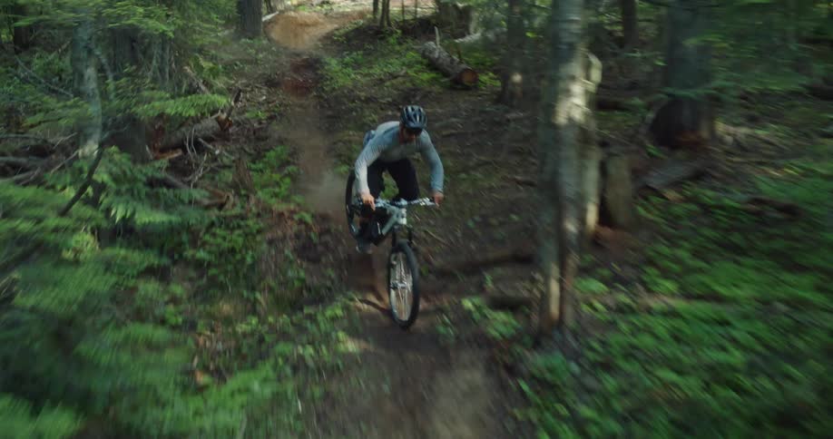 Man riding at high speed on his mountain bike going down a wooded trail with dynamic action