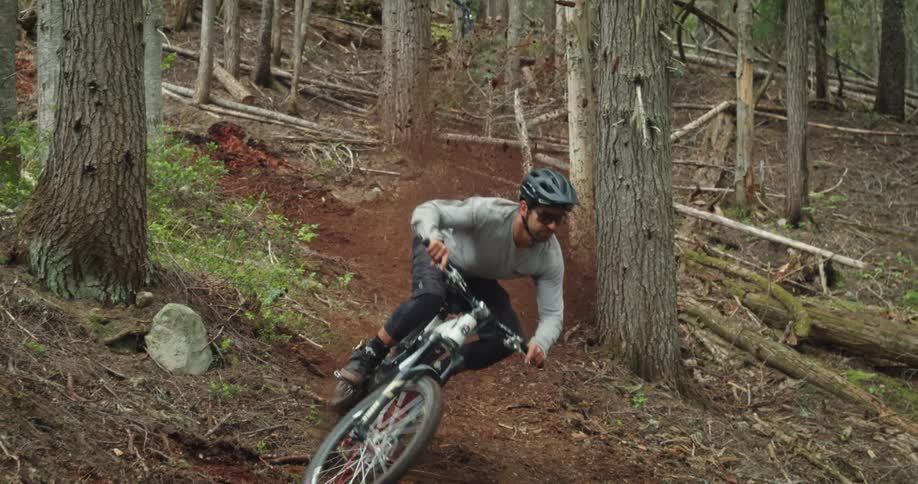 Mountain biker hits corner on riding trail causing an explosion of dirt and loam
