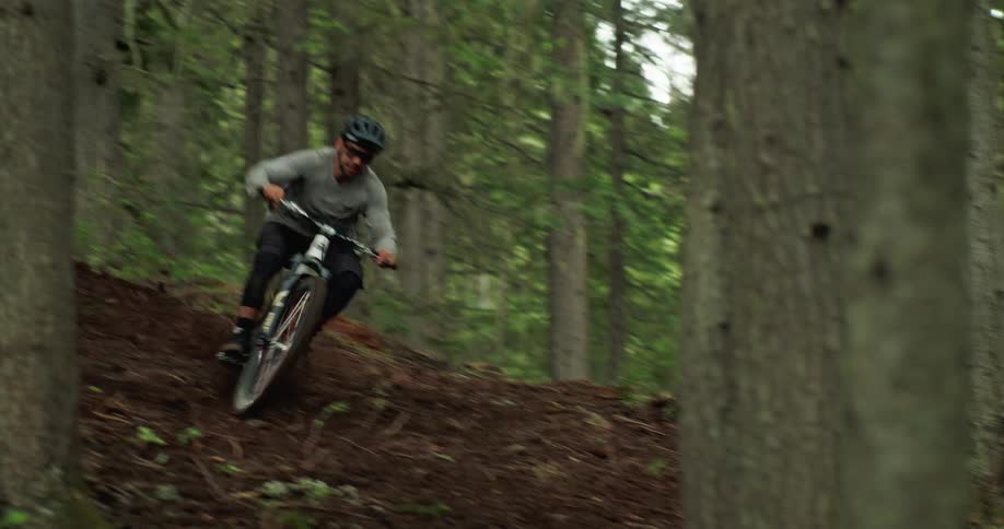 Man jumps his mountain bike sideways in the middle of the forest trail