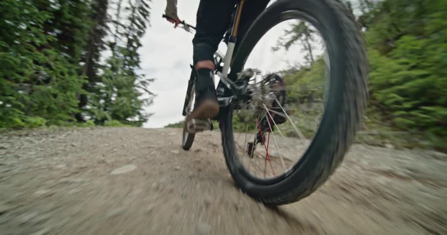Mountain bike athlete rides up a steep hill on a dirt road
