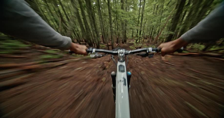 Point of view perspective of a man riding a mountain bike down a steep trail at a tremendous rate of speed