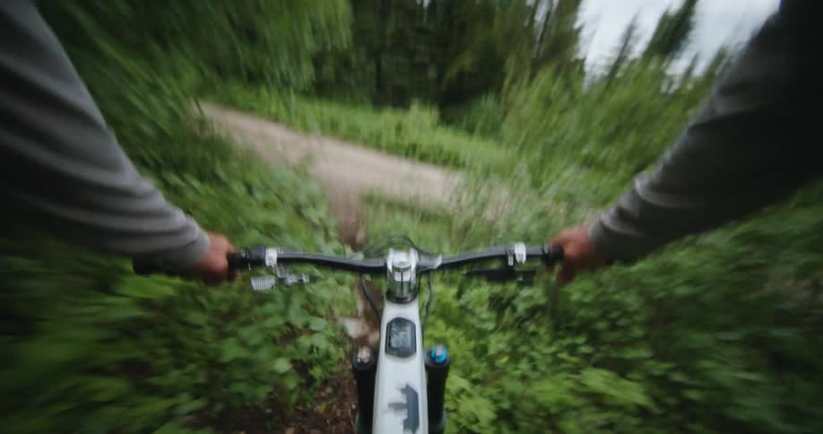 A person exits a mountain bike trail back onto the access road
