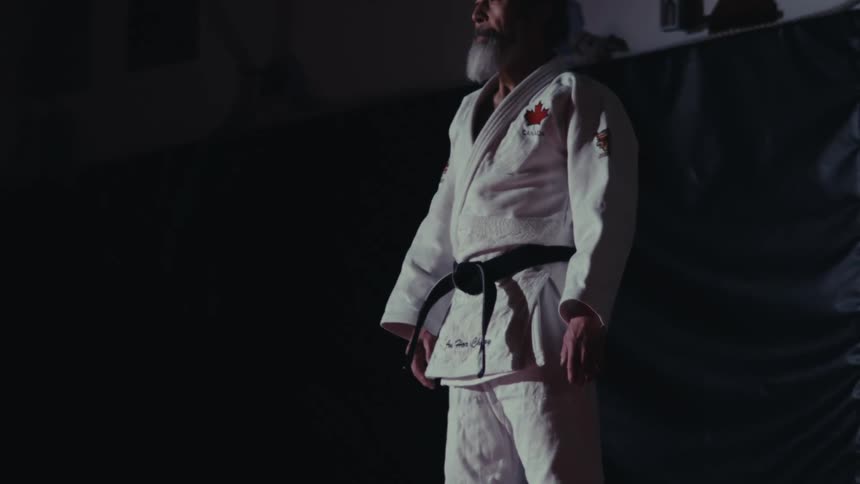 Man with a white beard wearing a kimono and a black belt standing static