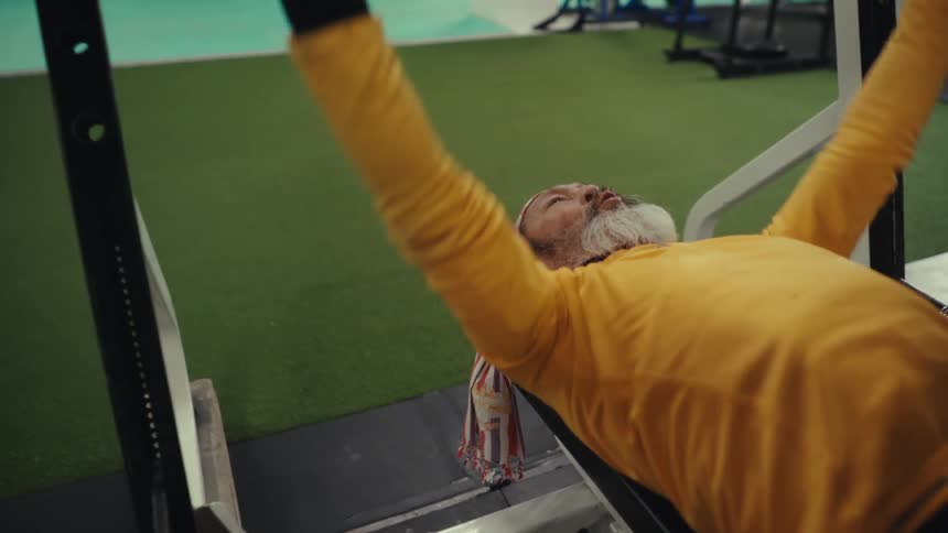 Concentrated man doing barbell with bench press
