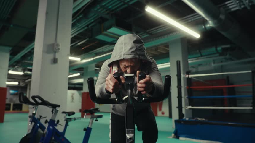 Concentrated man pedaling an exercise bike at the gym