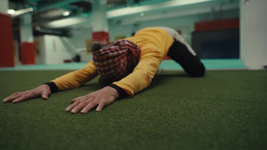 Man with his hands stretched out on a green rug stretching his body