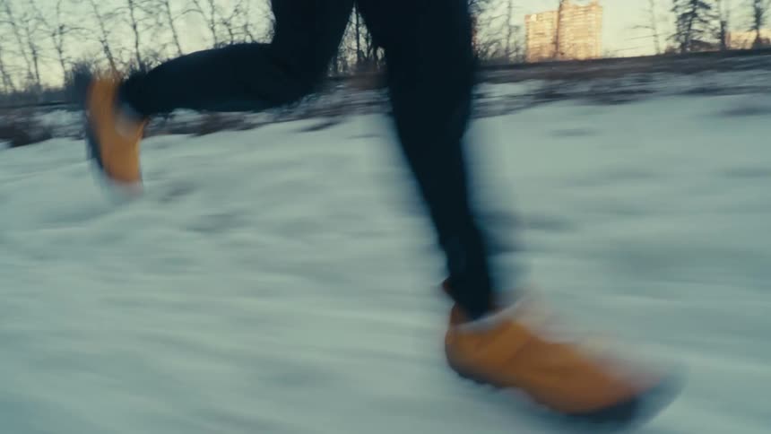 A person runs down a snow covered path next to a fence