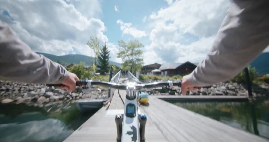 A person cycles across the lakeside dock