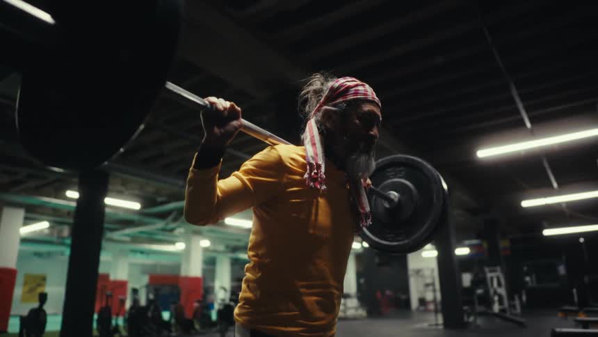 An older asian man is lifting weights in a gym