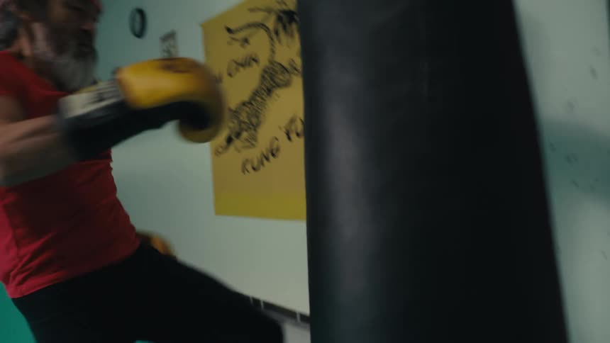 Man with gloves kicking and punching a punching bag