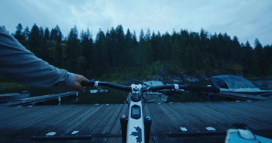 Point of view of a man taking a mountain bike off a boat and walking it along the dock