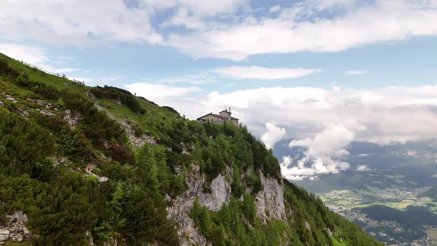 Aerial view of a mountainous valley with a building on the peak in the background