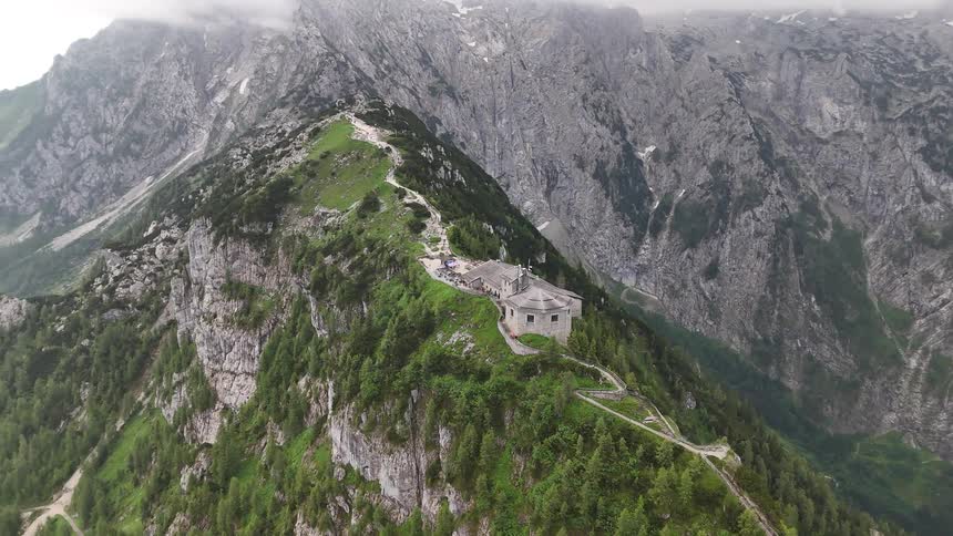 House sits on top of a narrow mountain peak with a driveway winding down