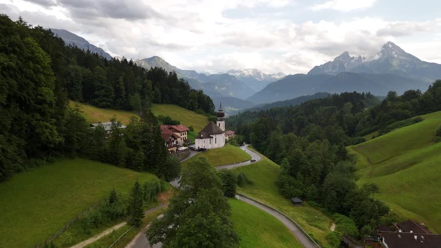 Vehicles drive along a highway passing through a town in a narrow valley