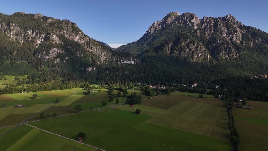 Farm fields and buildings in a rural area surrounded by a mountain range