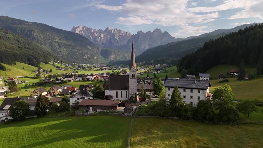 Village in greenish fields surrounded by a mountainous valley