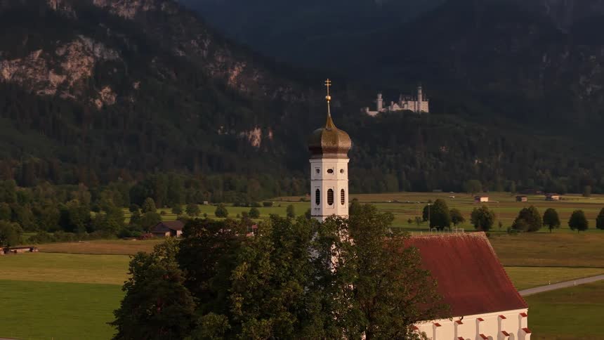 A church sits near other buildings and a road in a large mountain valley