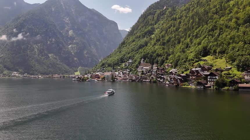 Boat heading towards a village on the shore of a lake and surrounded by a mountainous valley