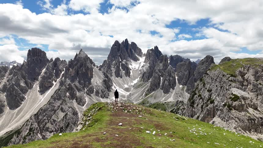 Person standing at the edge of a cliff looking at the massive mountain range across the canyon
