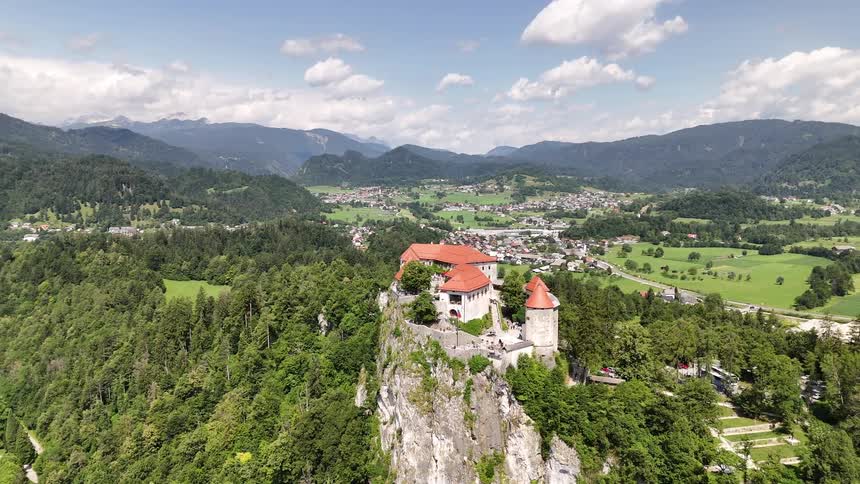 A castle with an orange roof and on top of a stony hill in front of a bay of water