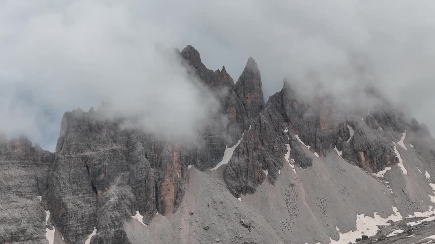Clouds slowly roll across tall jagged mountain peaks