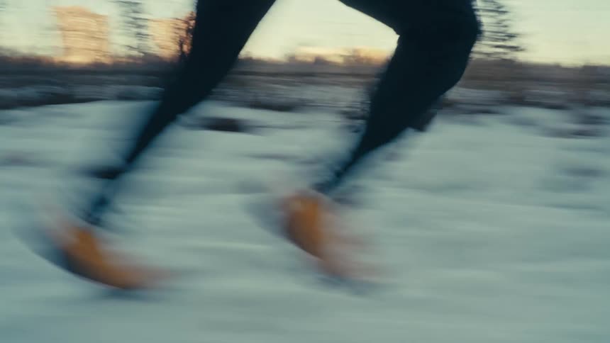A person runs on a snow covered path near a city
