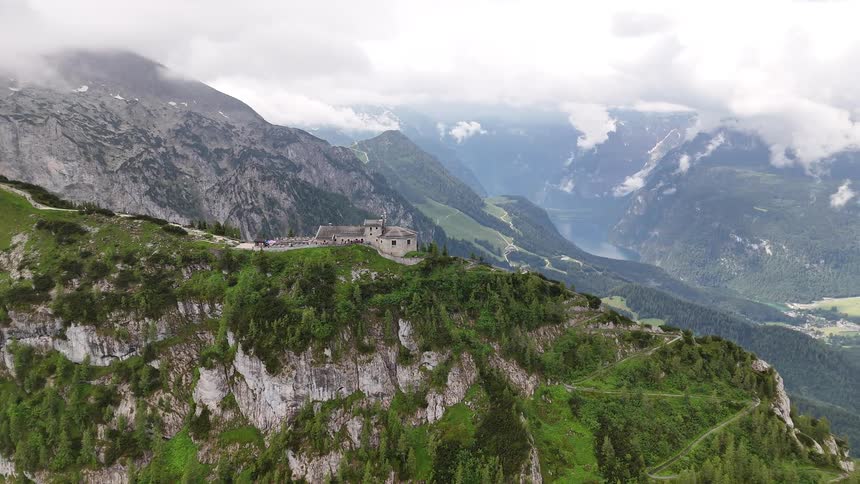 Fortress occupies forested ridge towering over a misty valley on a cloudy day