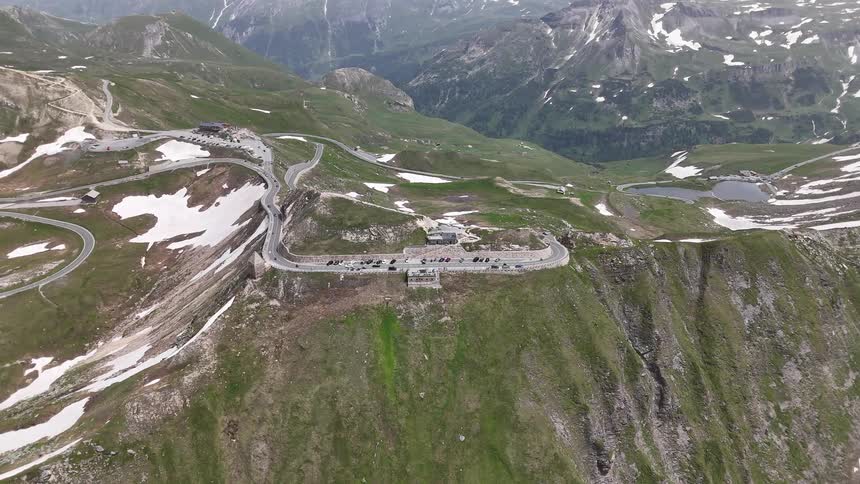 Aerial panorama of a snowy mountain valley and winding roads with vehicle traffic