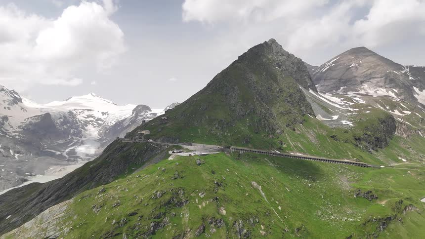 Road winding around the mountains to the snowy mountains behind