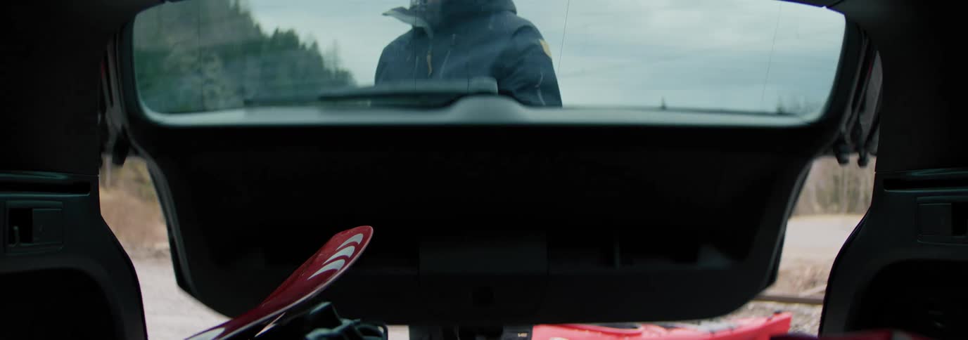 Man opening the trunk of a car taking equipment from a kayak and in the background a train passing by