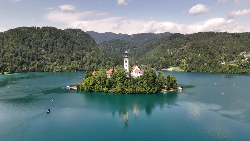Forest surrounds the church on an island near a coastal town surrounded by forested mountains
