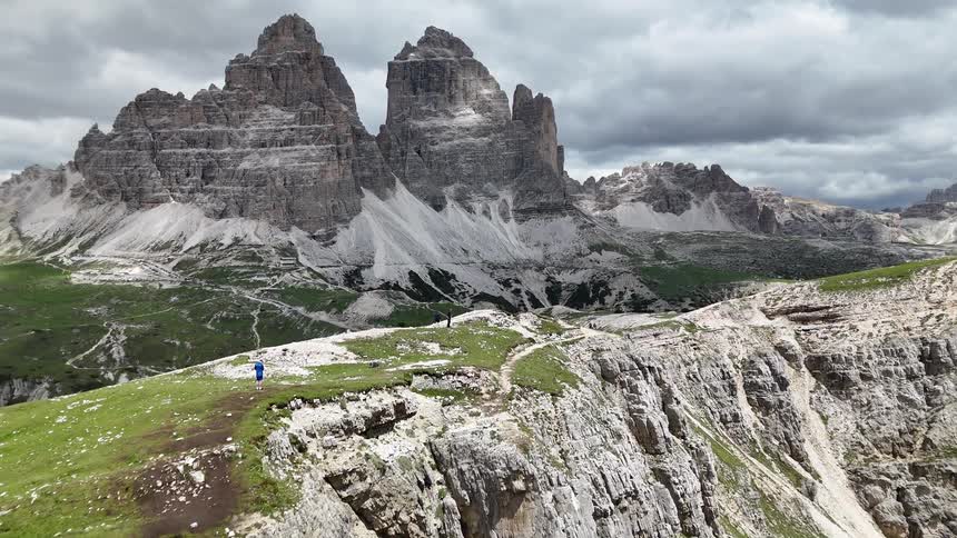 Hikers on top of a mountain overlooking a taller mountain on a cloudy day
