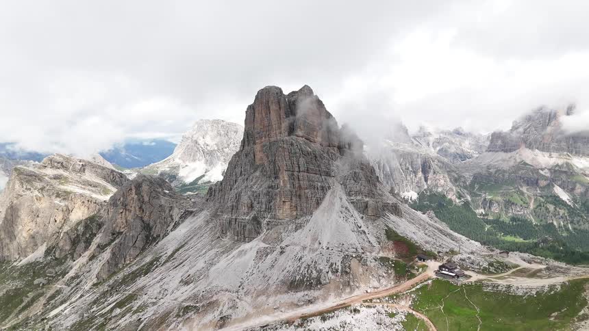 The clouds cover the peak of the tall mountain