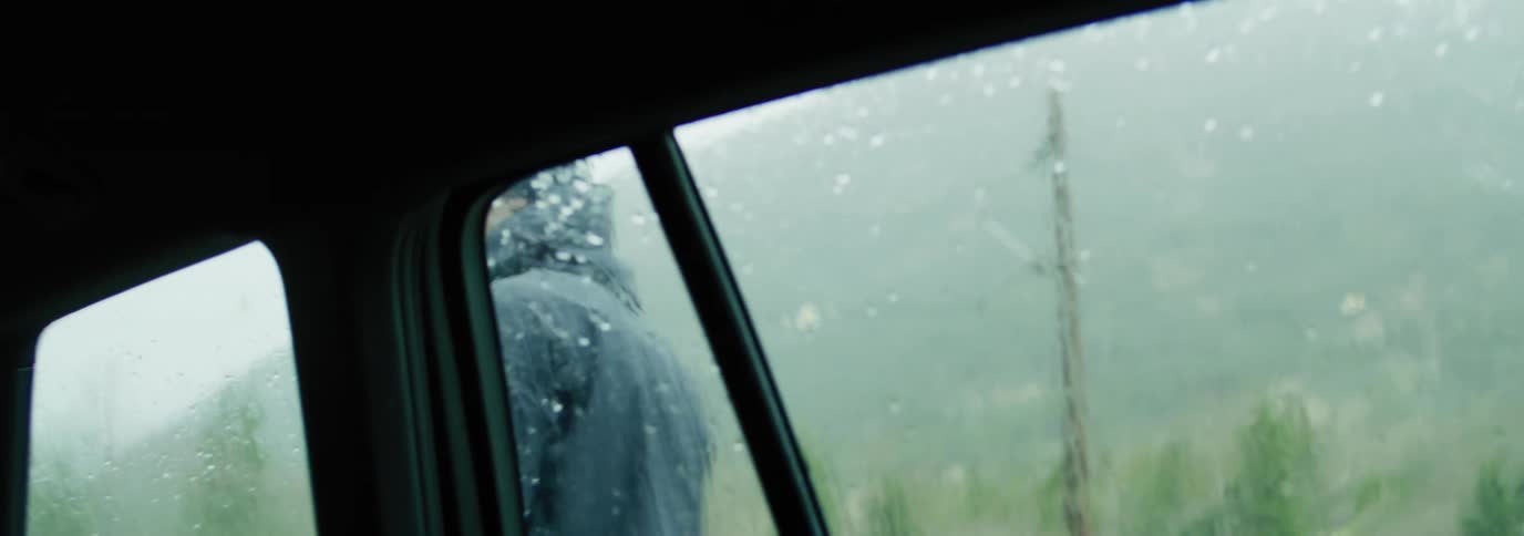 View from inside the car of a man outside removing a kayak from above