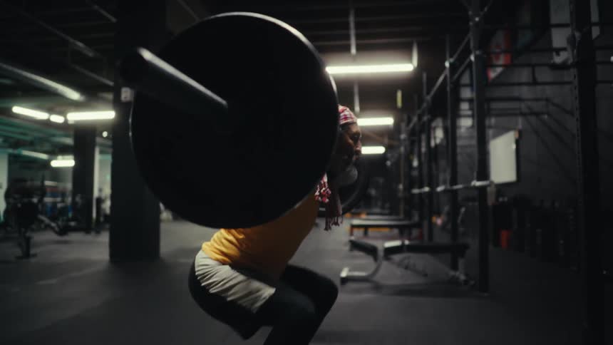 Older man lifts a heavy weight bar in an empty gym at night