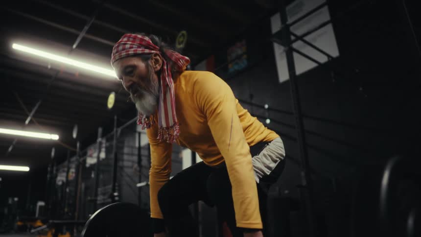 Concentrated man lifting weights on a barbell with weight plates in a gym